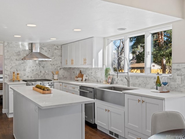 kitchen featuring dark hardwood / wood-style flooring, stainless steel appliances, wall chimney range hood, white cabinets, and a center island