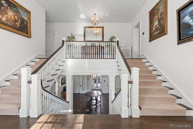 stairs with hardwood / wood-style floors and a notable chandelier