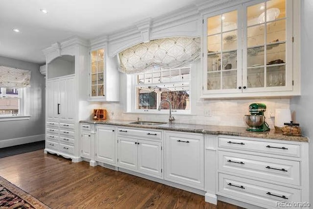 bar with sink, dark hardwood / wood-style floors, light stone counters, white cabinets, and decorative backsplash