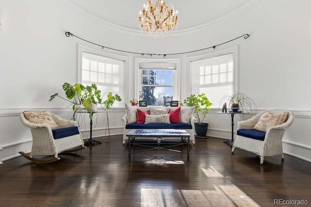 living area with crown molding, dark wood-type flooring, and a notable chandelier