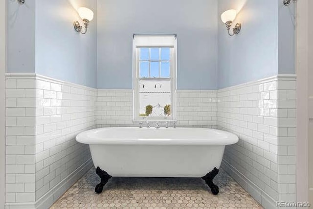 bathroom featuring a washtub, tile patterned floors, and tile walls