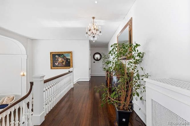 hallway with dark hardwood / wood-style floors and a notable chandelier