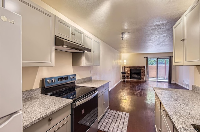 2223 S Buckley Rd Unit 102, Aurora, CO 80013 - kitchen with stainless steel range with electric cooktop, freestanding refrigerator, under cabinet range hood, open floor plan, and a fireplace