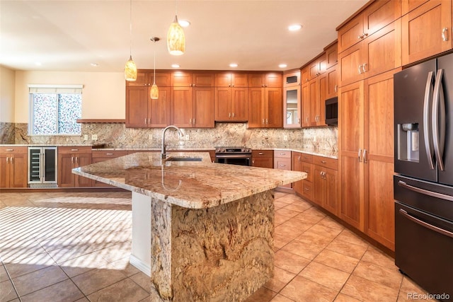 kitchen with sink, hanging light fixtures, beverage cooler, stainless steel appliances, and a center island with sink