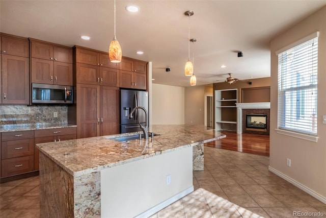 kitchen with pendant lighting, an island with sink, stainless steel appliances, and light tile patterned floors