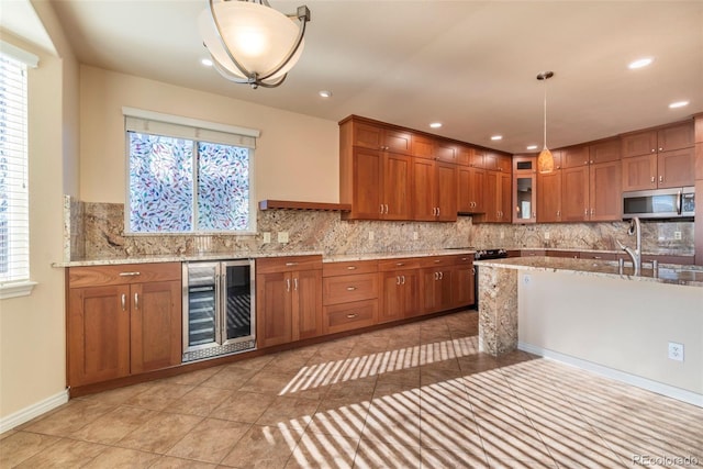 kitchen featuring pendant lighting, backsplash, light tile patterned floors, light stone counters, and beverage cooler