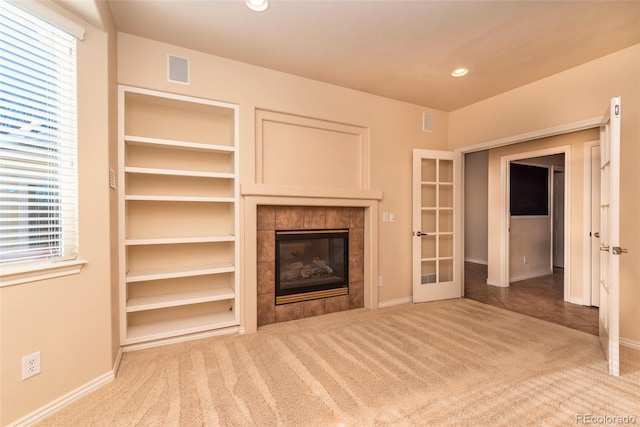 unfurnished living room featuring carpet flooring, a tile fireplace, and french doors