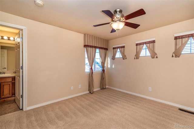 carpeted spare room with ceiling fan and sink