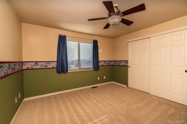 unfurnished bedroom featuring ceiling fan, light carpet, and a closet