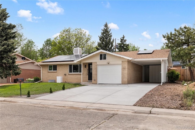 ranch-style home with a front yard, cooling unit, solar panels, and a garage