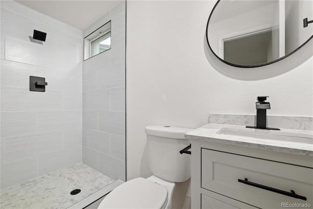 bathroom with toilet, vanity, and tiled shower