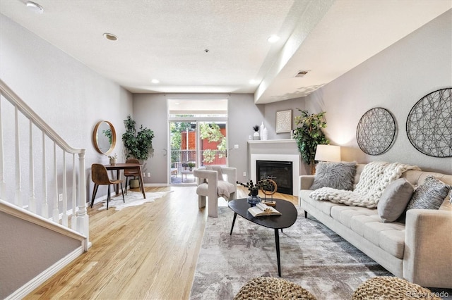 3030 Wyandot St Unit 4, Denver, CO 80211 - living room featuring wood finished floors, a glass covered fireplace, baseboards, stairs, and a textured ceiling