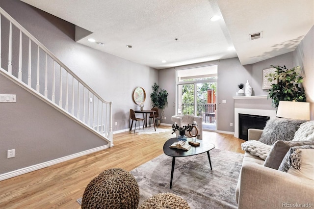 3030 Wyandot St Unit 4, Denver, CO 80211 - living room with wood finished floors, stairs, baseboards, a glass covered fireplace, and a textured ceiling