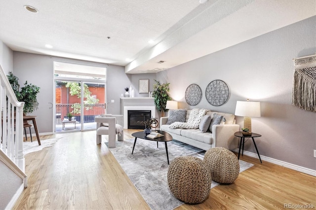 3030 Wyandot St Unit 4, Denver, CO 80211 - living area with wood finished floors, baseboards, a textured ceiling, a glass covered fireplace, and stairs