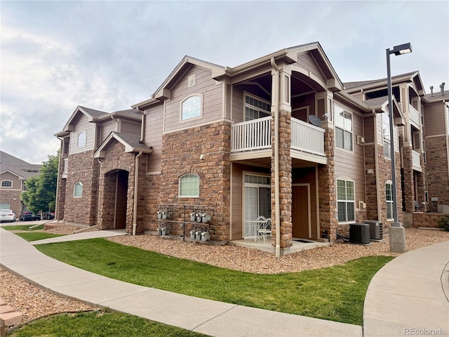 7440 S Blackhawk St Unit 9-108, Englewood, CO 80112 - view of front facade with a balcony, stone siding, central air condition unit, and a front yard