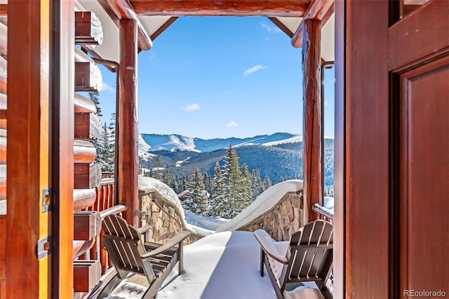 snow covered back of property featuring a mountain view