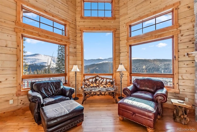 sitting room with hardwood / wood-style floors, a towering ceiling, a mountain view, and a healthy amount of sunlight