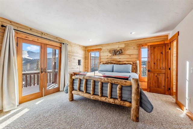 carpeted bedroom with access to outside, recessed lighting, wood walls, french doors, and a mountain view