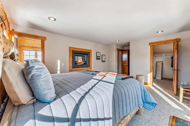 bedroom featuring a closet, recessed lighting, a glass covered fireplace, and carpet floors