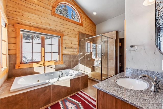 bathroom featuring a whirlpool tub, vanity, vaulted ceiling, a stall shower, and wood walls