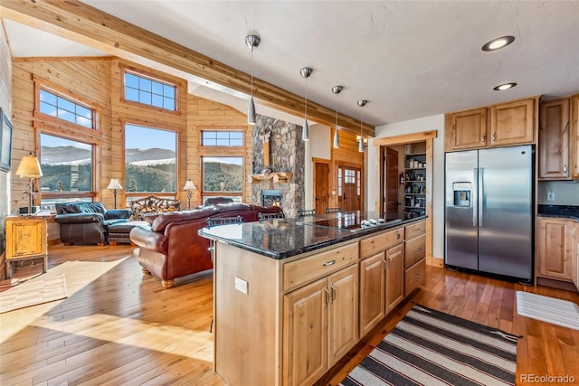 kitchen with stainless steel fridge, black electric cooktop, open floor plan, wooden walls, and light wood-style flooring