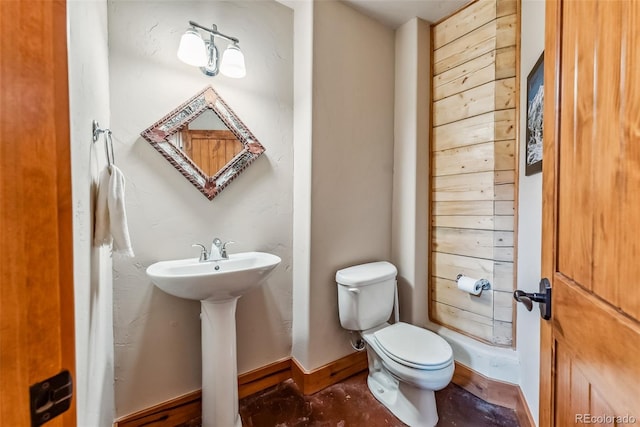 half bathroom featuring toilet, a sink, and baseboards