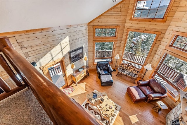 living room featuring wood finished floors, wooden walls, and high vaulted ceiling