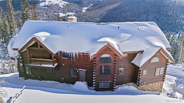 exterior space featuring a mountain view, a chimney, and log siding