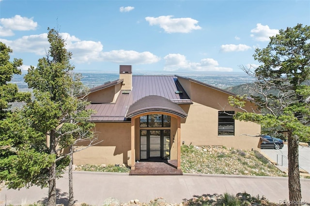 784 Grand Horizon Vw, Manitou Springs, CO 80829 - view of front of home featuring a standing seam roof, metal roof, stucco siding, a chimney, and a water view