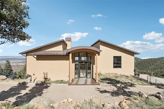 784 Grand Horizon Vw, Manitou Springs, CO 80829 - rear view of house with stucco siding, a standing seam roof, metal roof, a mountain view, and a chimney