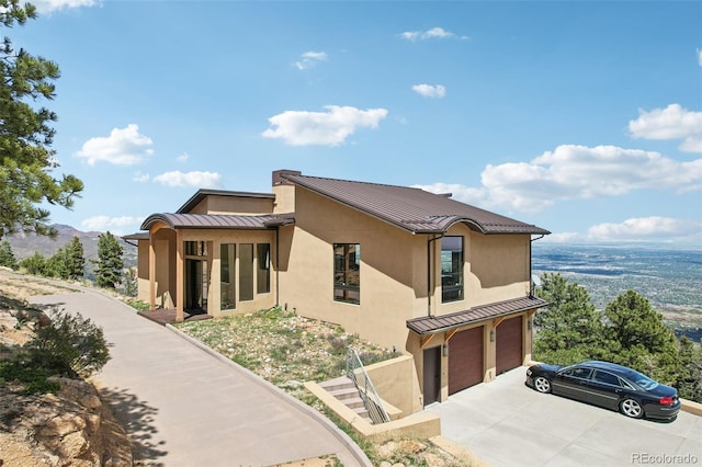 784 Grand Horizon Vw, Manitou Springs, CO 80829 - view of home's exterior featuring a standing seam roof, metal roof, a garage, stucco siding, and concrete driveway