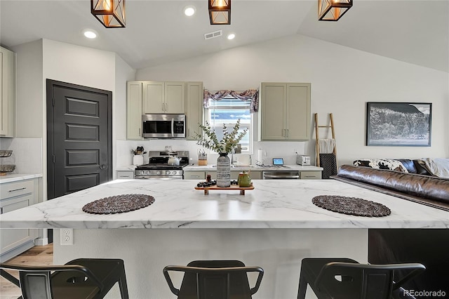 kitchen with light stone countertops, appliances with stainless steel finishes, a center island, and a breakfast bar area