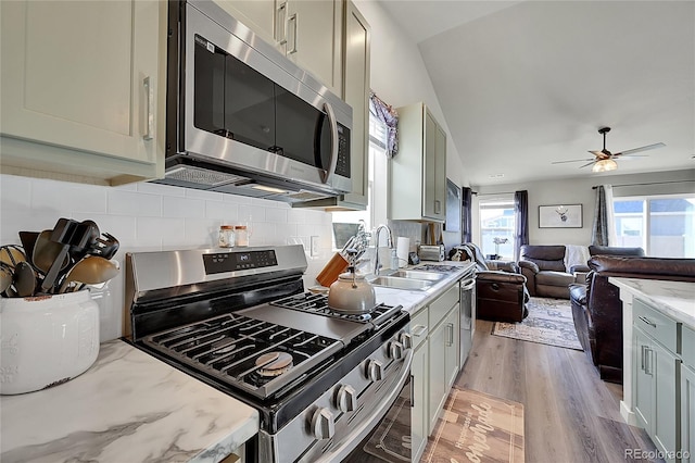 kitchen with tasteful backsplash, appliances with stainless steel finishes, gray cabinets, and light stone counters