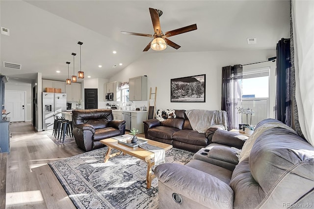 living room with light hardwood / wood-style flooring, a wealth of natural light, lofted ceiling, and ceiling fan