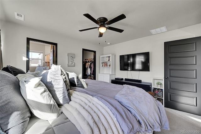 carpeted bedroom featuring a walk in closet, a closet, ceiling fan, and ensuite bathroom