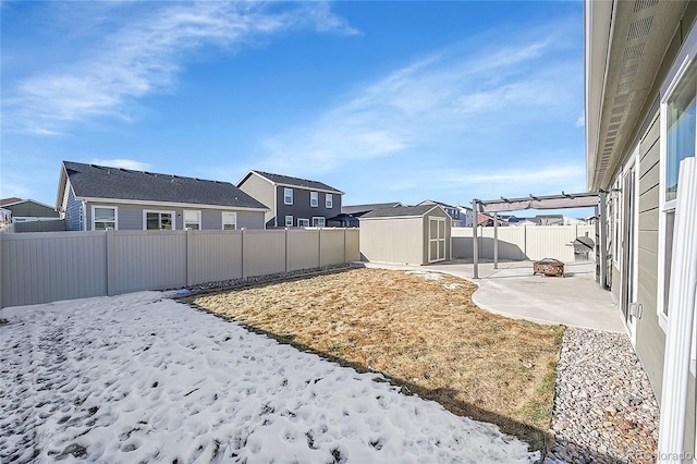 snowy yard featuring a patio area and a storage unit