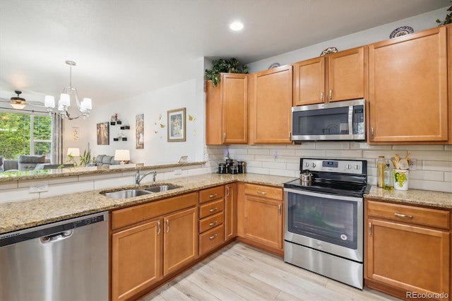 kitchen with sink, ceiling fan, appliances with stainless steel finishes, tasteful backsplash, and light hardwood / wood-style floors