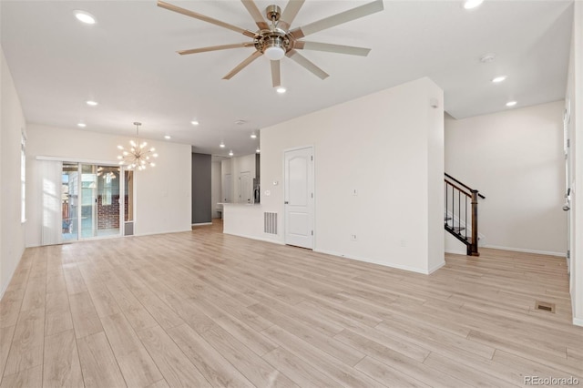 unfurnished living room featuring light wood-style flooring, recessed lighting, ceiling fan with notable chandelier, baseboards, and stairs