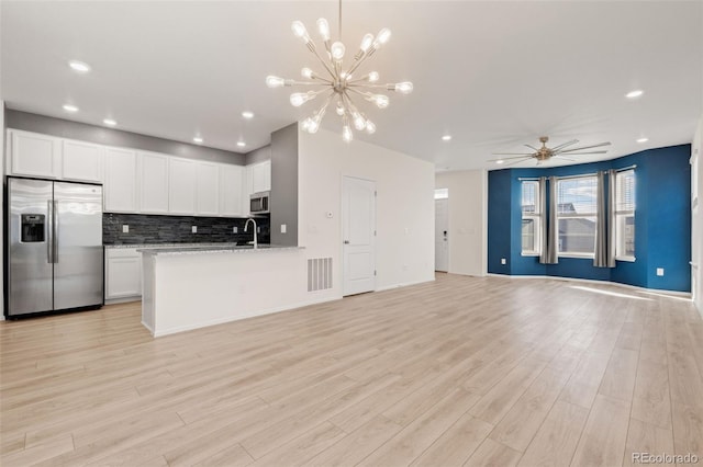 kitchen featuring appliances with stainless steel finishes, open floor plan, visible vents, and decorative backsplash