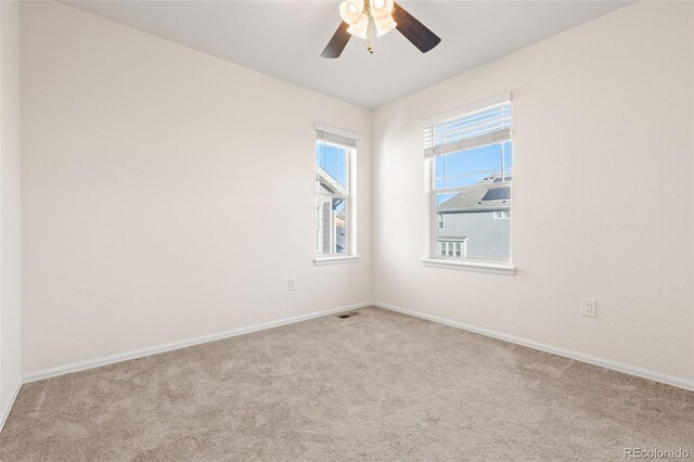 carpeted spare room with ceiling fan, visible vents, and baseboards