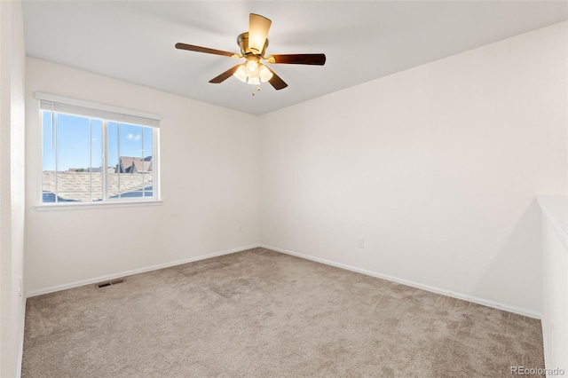 carpeted empty room with baseboards, visible vents, and a ceiling fan