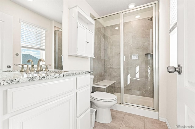 bathroom with a stall shower, vanity, toilet, and tile patterned floors