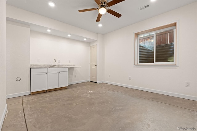 bar with concrete flooring, a sink, visible vents, and baseboards