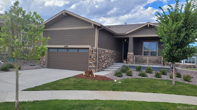 22345 E Bailey Pl, Aurora, CO 80016 - craftsman house with a porch, concrete driveway, stone siding, and a front yard