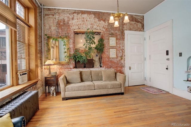 living room with radiator, an inviting chandelier, and brick wall