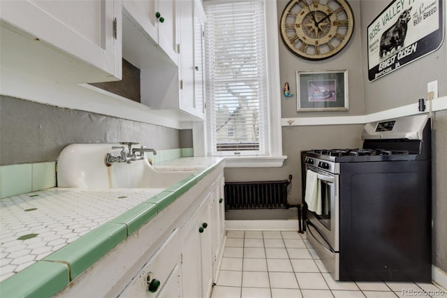 kitchen with tile countertops, white cabinetry, stainless steel range with gas stovetop, and light tile patterned floors