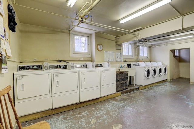 clothes washing area with separate washer and dryer, a wealth of natural light, and sink