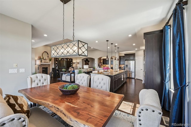 27423 E Euclid Dr, Aurora, CO 80016 - dining space featuring dark wood-style floors, a fireplace, recessed lighting, and arched walkways