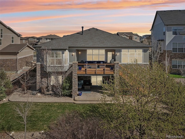 27423 E Euclid Dr, Aurora, CO 80016 - back of property at dusk with a patio area, roof with shingles, stone siding, stairway, and a wooden deck