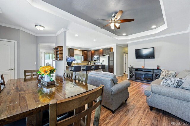 6231 Indian Paintbrush St Unit 214, Frederick, CO 80530 - living area featuring light wood-style flooring, a ceiling fan, a tray ceiling, recessed lighting, and ornamental molding